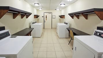 A laundry facility with multiple washing machines, a door, and overhead lighting.