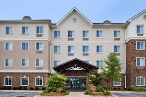 A multi-story hotel with a central entrance, a stone facade on one side, and a uniform window pattern.