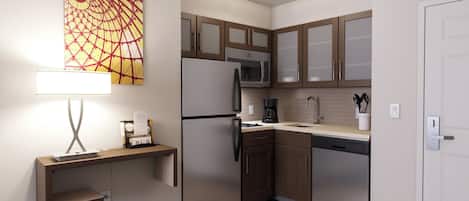 A modern kitchen with a refrigerator, microwave, coffee maker, and wooden cabinets.