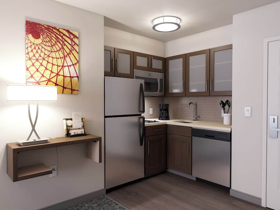 Una cocina moderna con refrigerador, microondas, cafetera y gabinetes de madera.