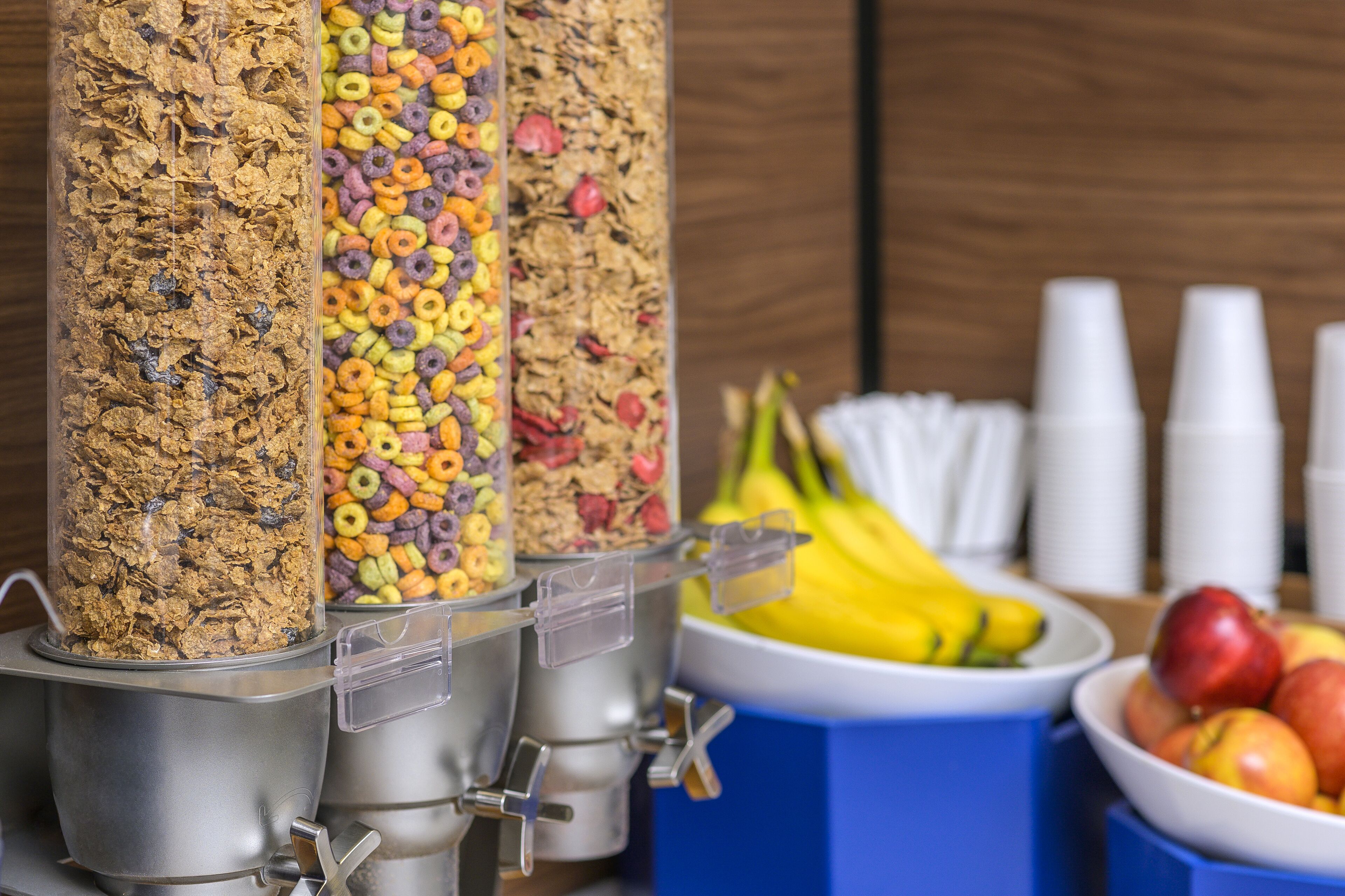 A breakfast bar with cereal dispensers and a fruit bowl.