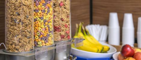 A breakfast bar with cereal dispensers and a fruit bowl.