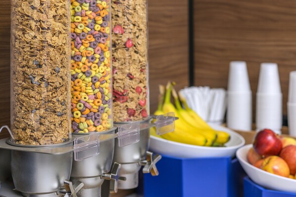 A breakfast bar with cereal dispensers and a fruit bowl.