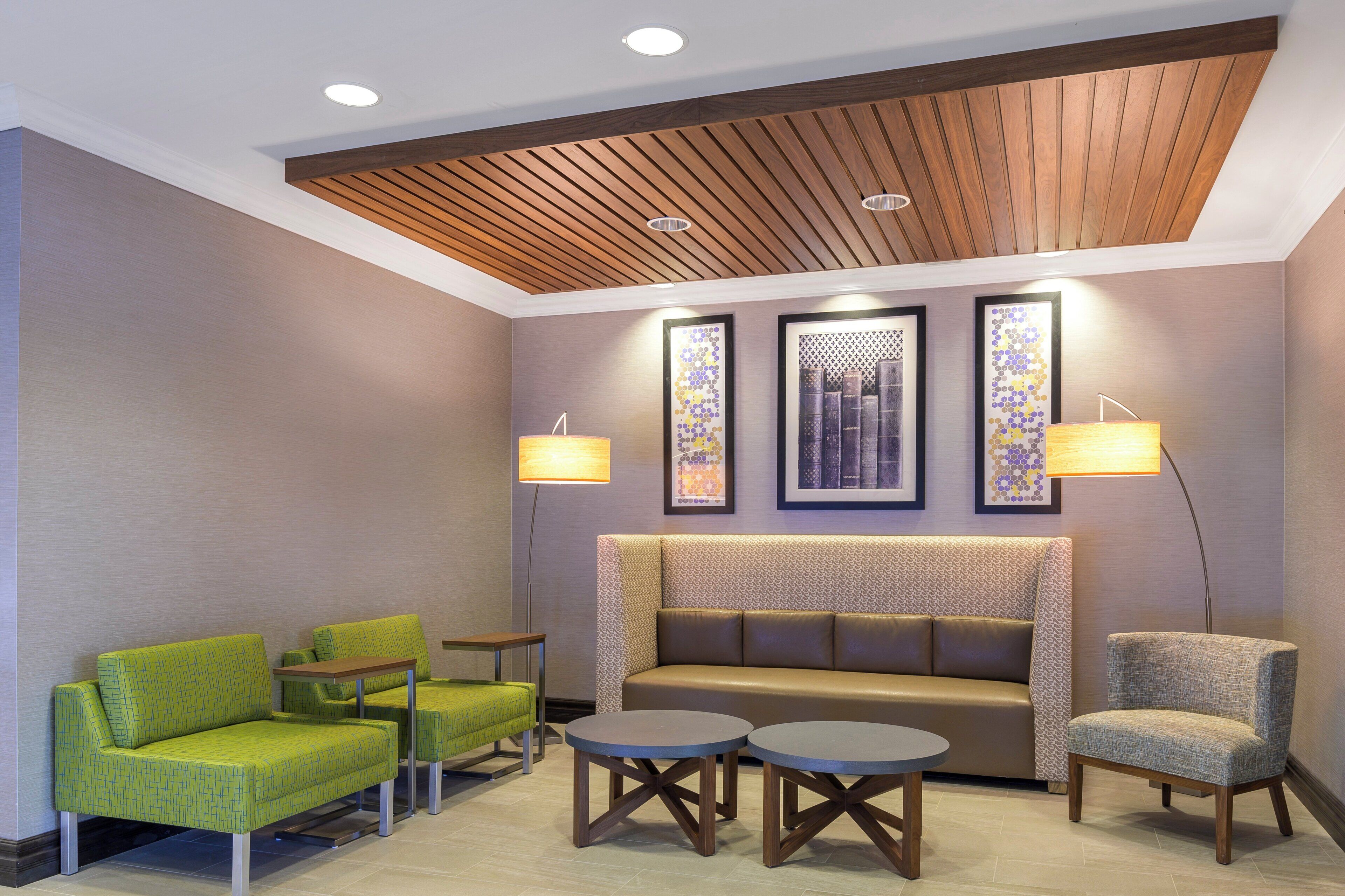Un hall d’entrée avec un plafond en bois, un canapé, deux fauteuils, une petite table et des œuvres d’art murales.