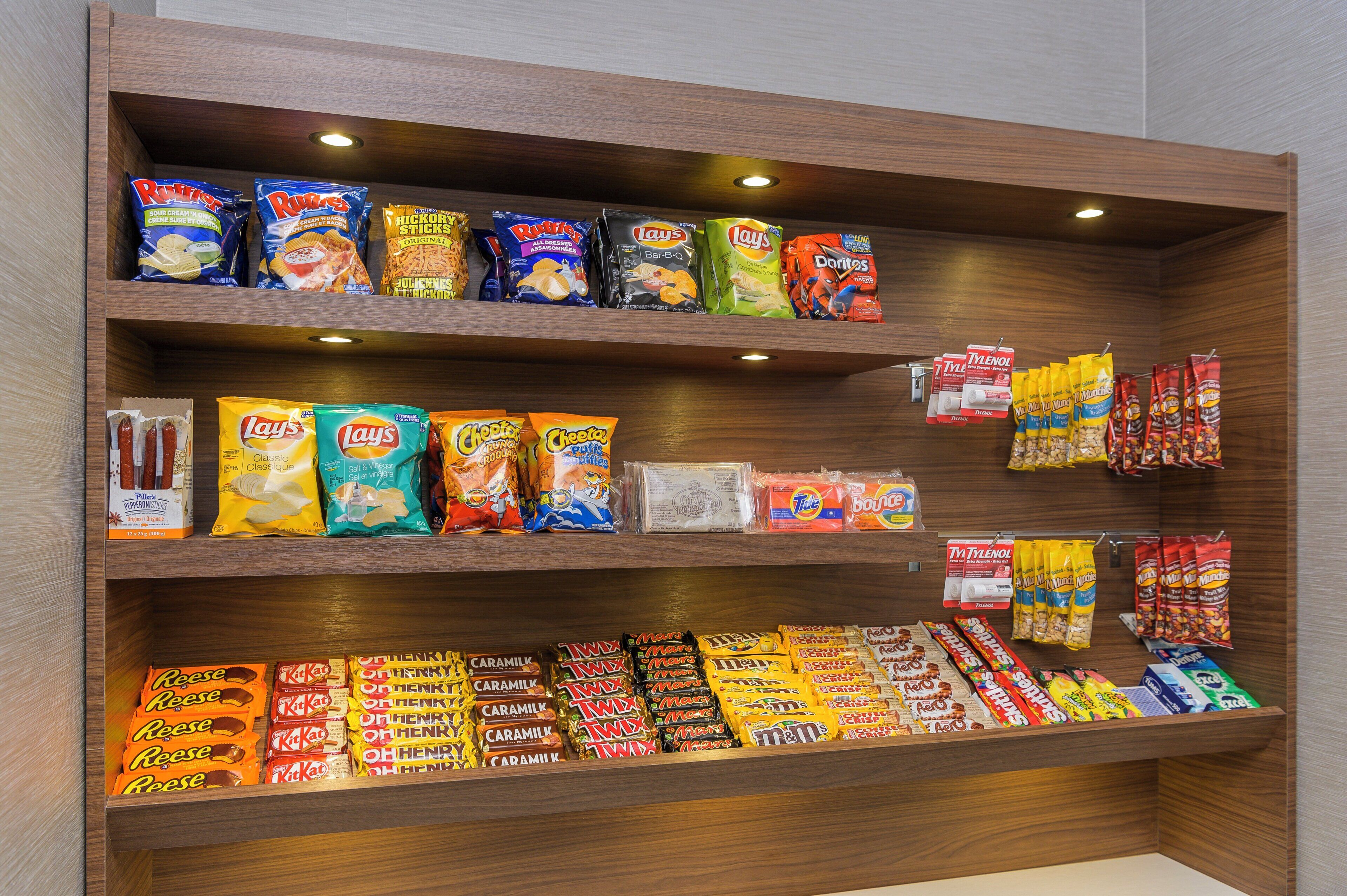 Un présentoir proposant une variété de marques et de types de croustilles, de biscuits salés et de bonbons.