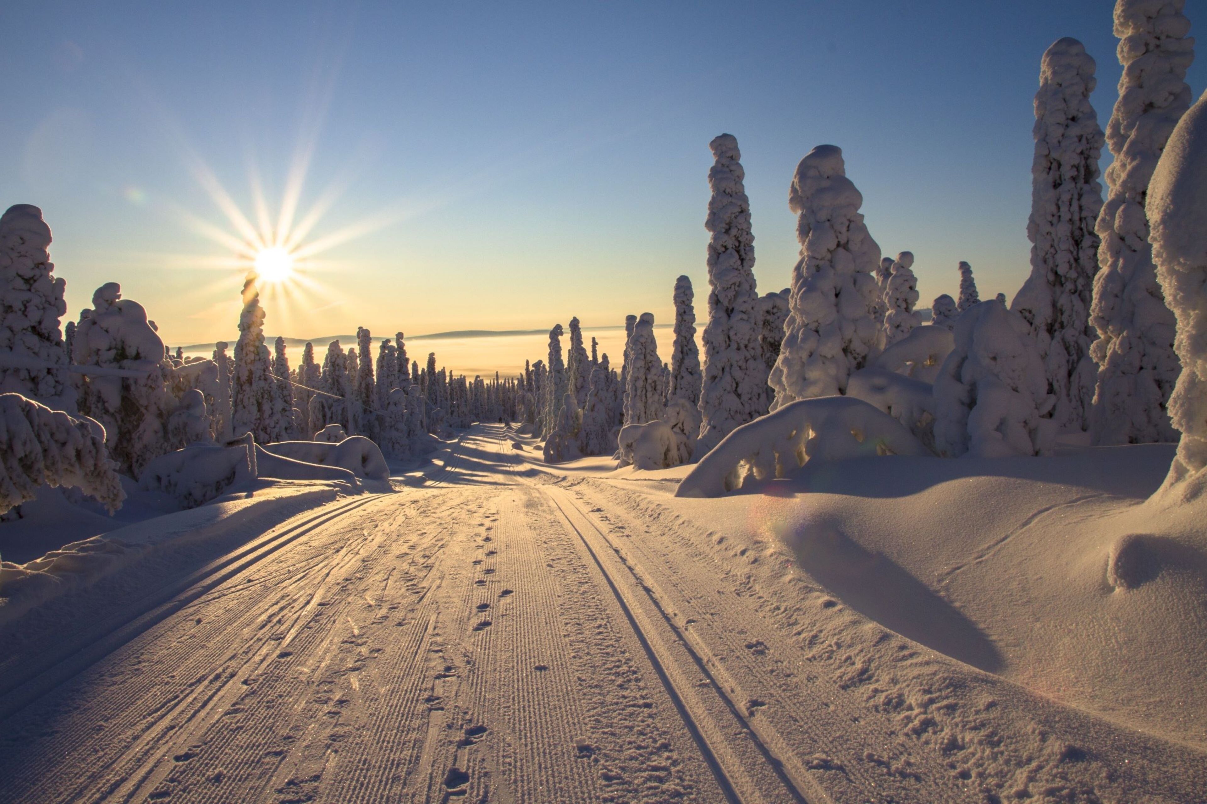 A snowy landscape with a clear sky and the sun shining.