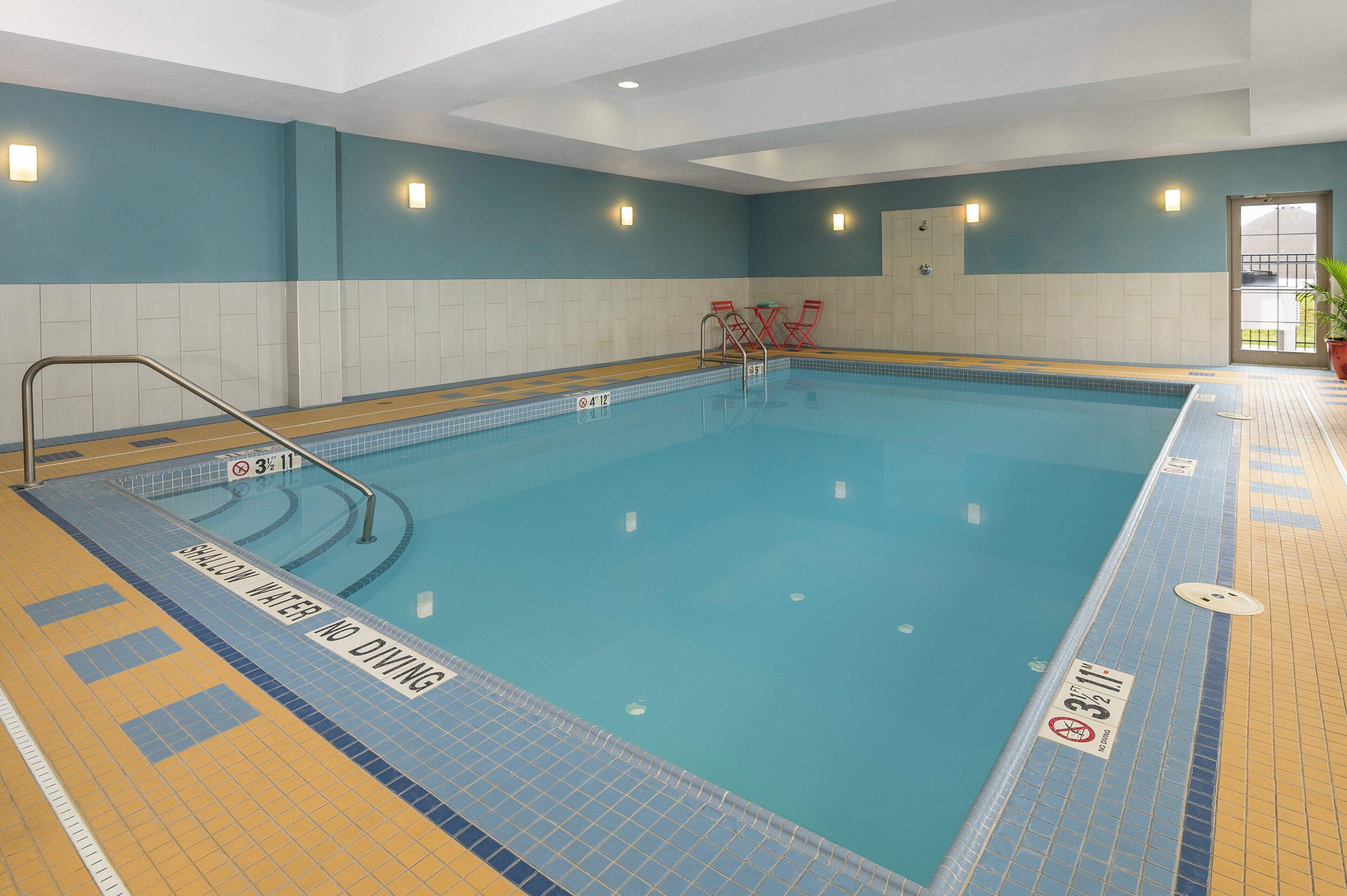 An indoor swimming pool with clear water, a no diving sign, and a no diving sign.