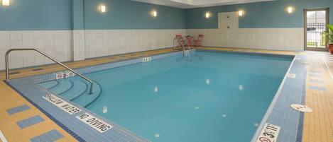 An indoor swimming pool with clear water, a no diving sign, and a no diving sign.