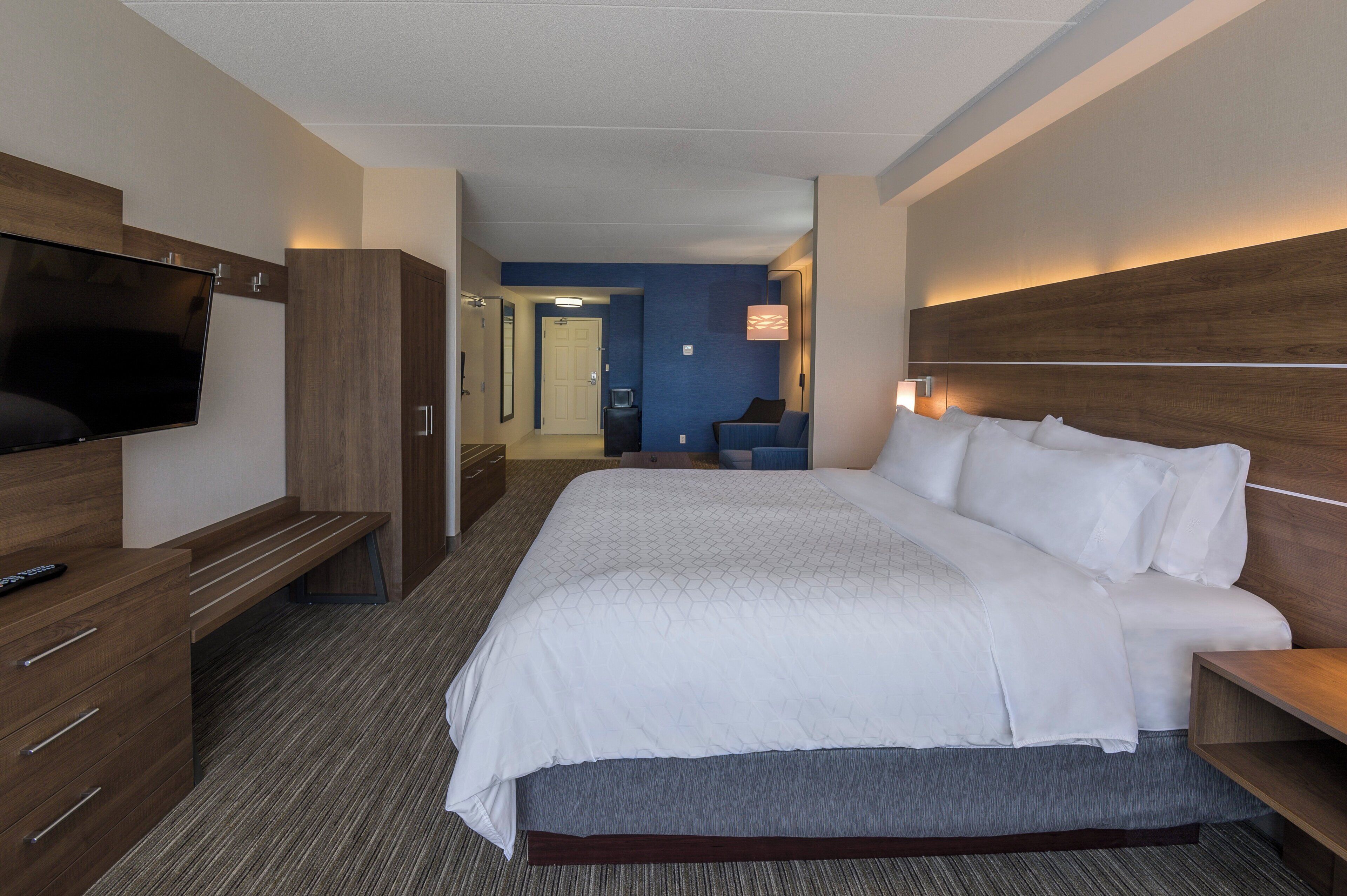 A hotel room with a large bed, a TV, a desk, and a chair.