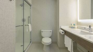 Un baño moderno con cabina de ducha de vidrio, inodoro y tocador con espejo.