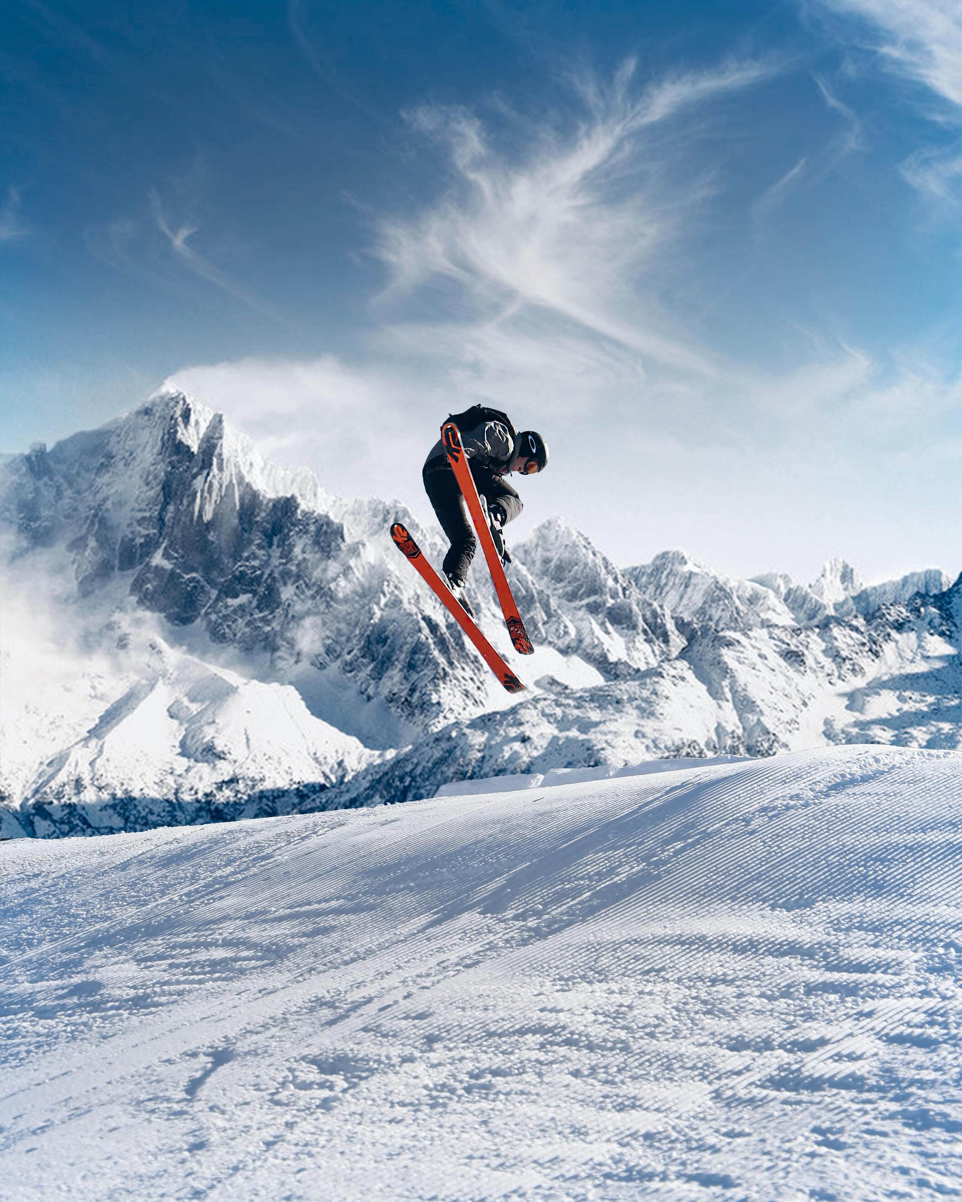 Un skieur en plein saut, avec en arrière-plan une montagne enneigée.
