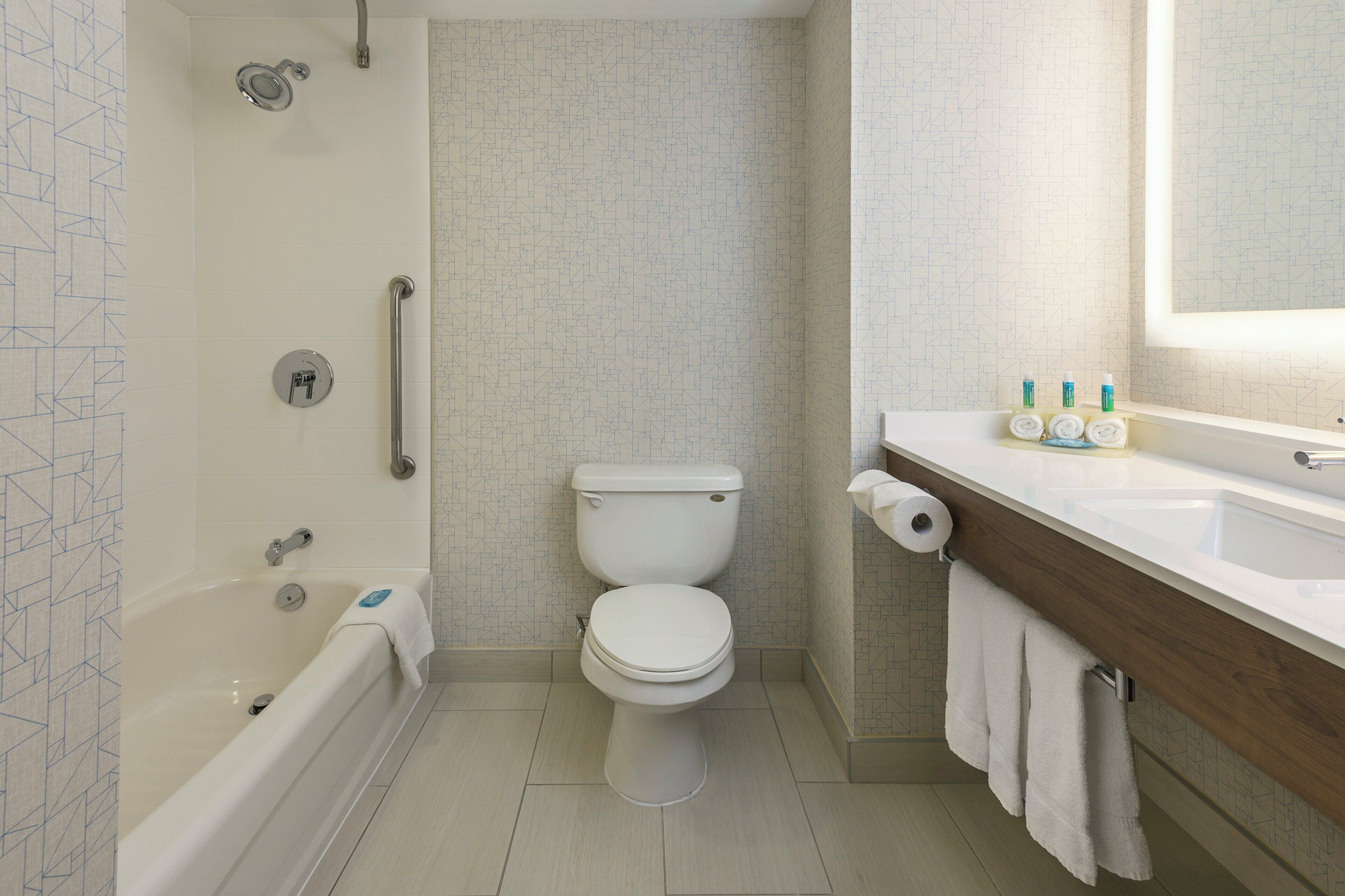 A bathroom with a bathtub, toilet, and a vanity with toiletries.