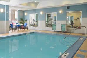 En swimmingpool med en skylt som förbjuder dykning, ett omklädningsrum med en spegel och en sittgrupp med stolar och ett bord.