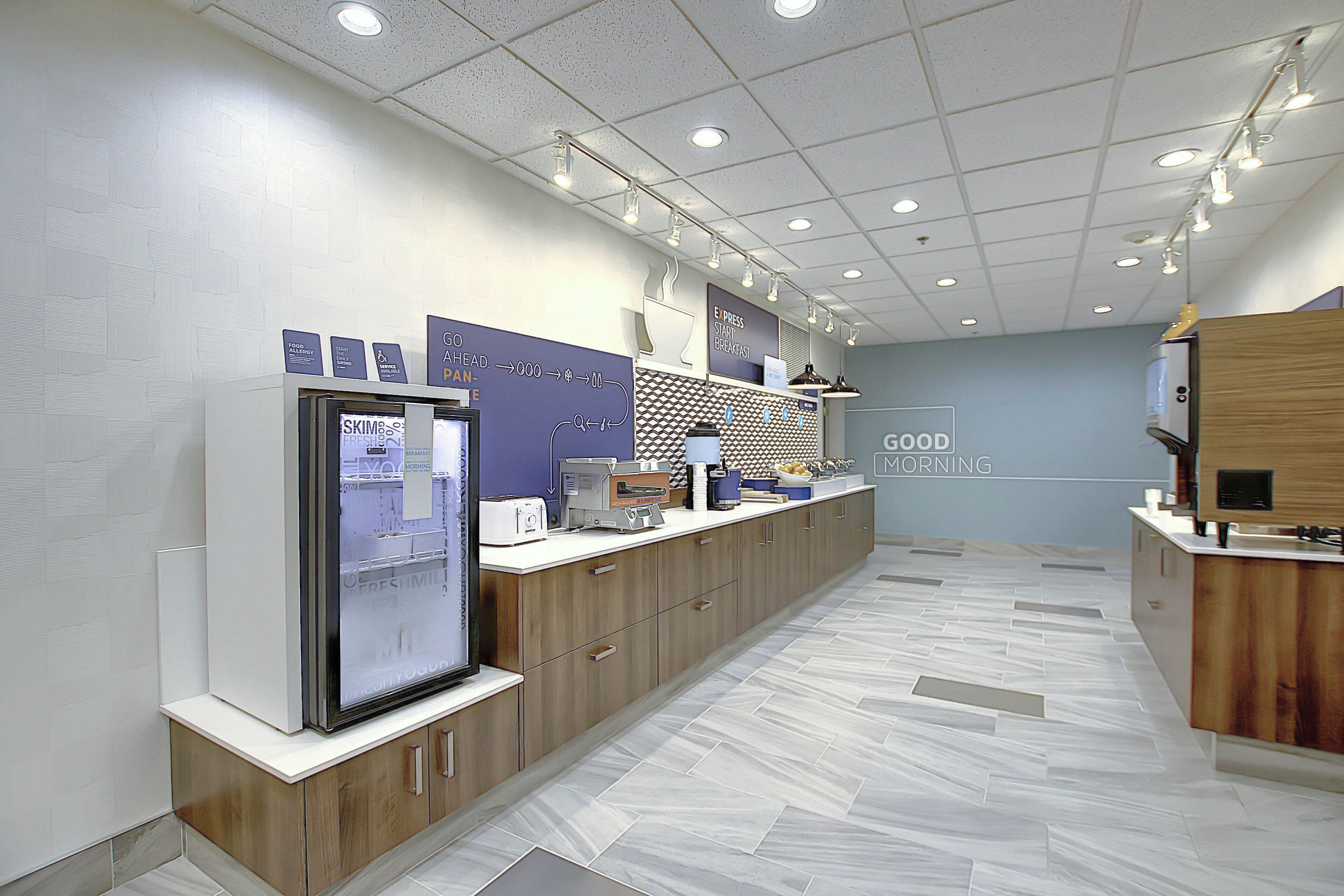A modern kitchen with a refrigerator, microwave, and a breakfast bar.