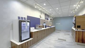 A modern kitchen with a refrigerator, microwave, and a breakfast bar.