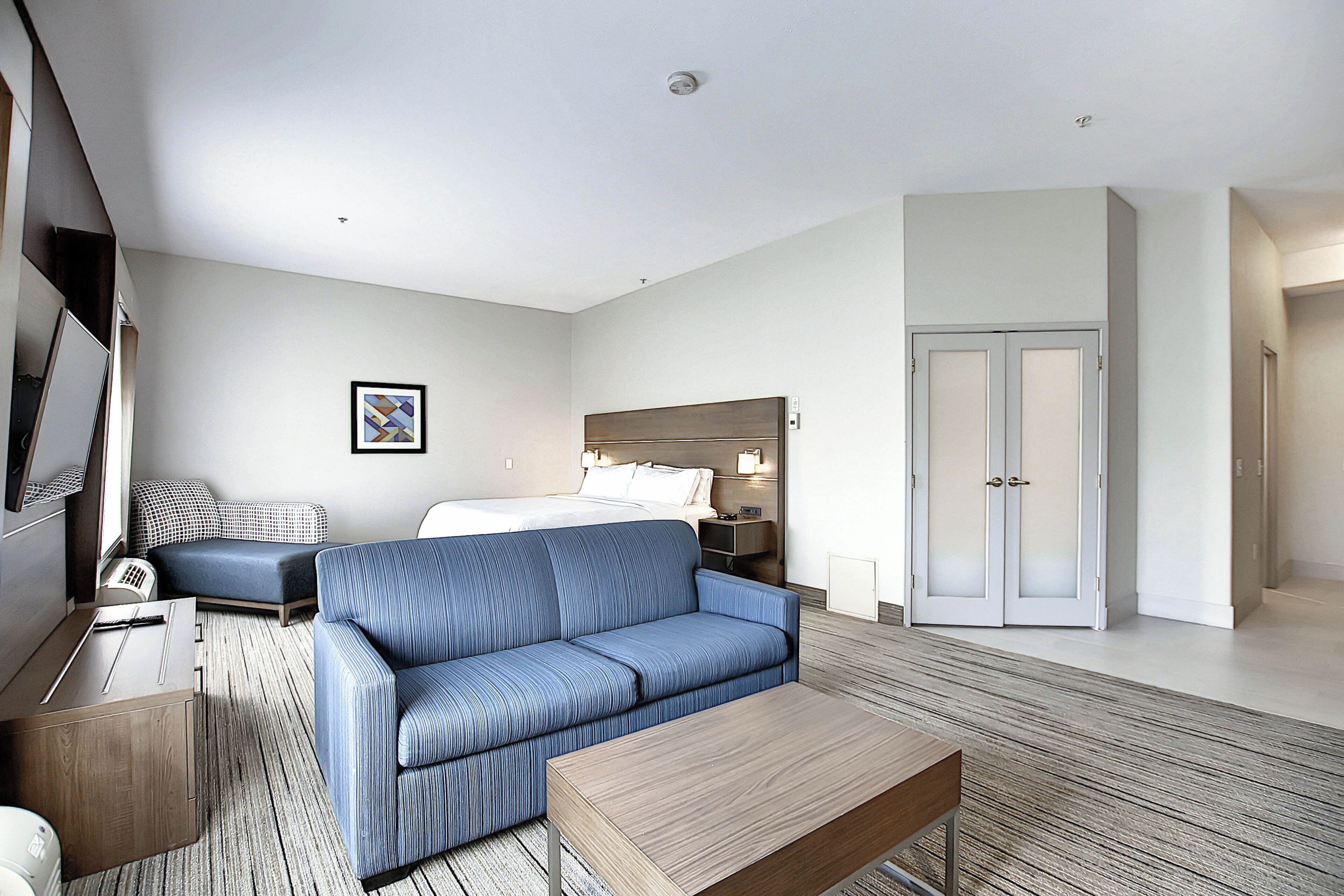 A hotel room with a bed, a sofa, a desk, a TV, and a wardrobe.