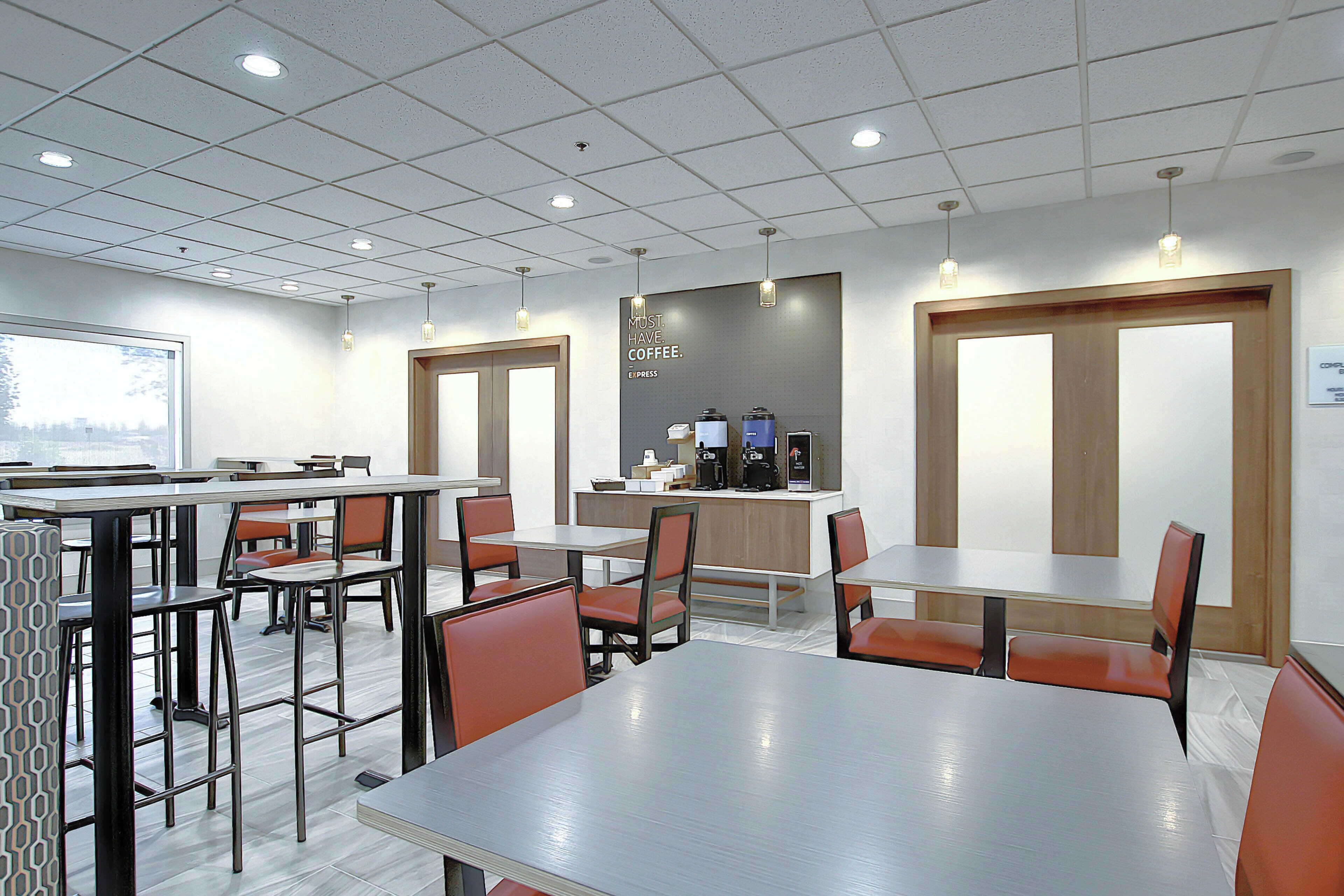 A modern cafe with tables and chairs, a coffee machine, and a sign that says 'MUST HAVE COFFEE.'