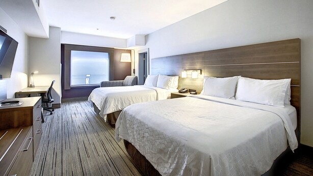A hotel room with two beds, a desk, a chair, a TV, and a window with a view. - Holiday Inn Express Airport-Calgary by IHG (Calgary)