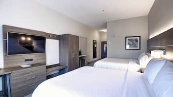 Ein Hotelzimmer mit einem großen Bett, einem Fernseher, einem Schreibtisch und einem Kleiderschrank.
