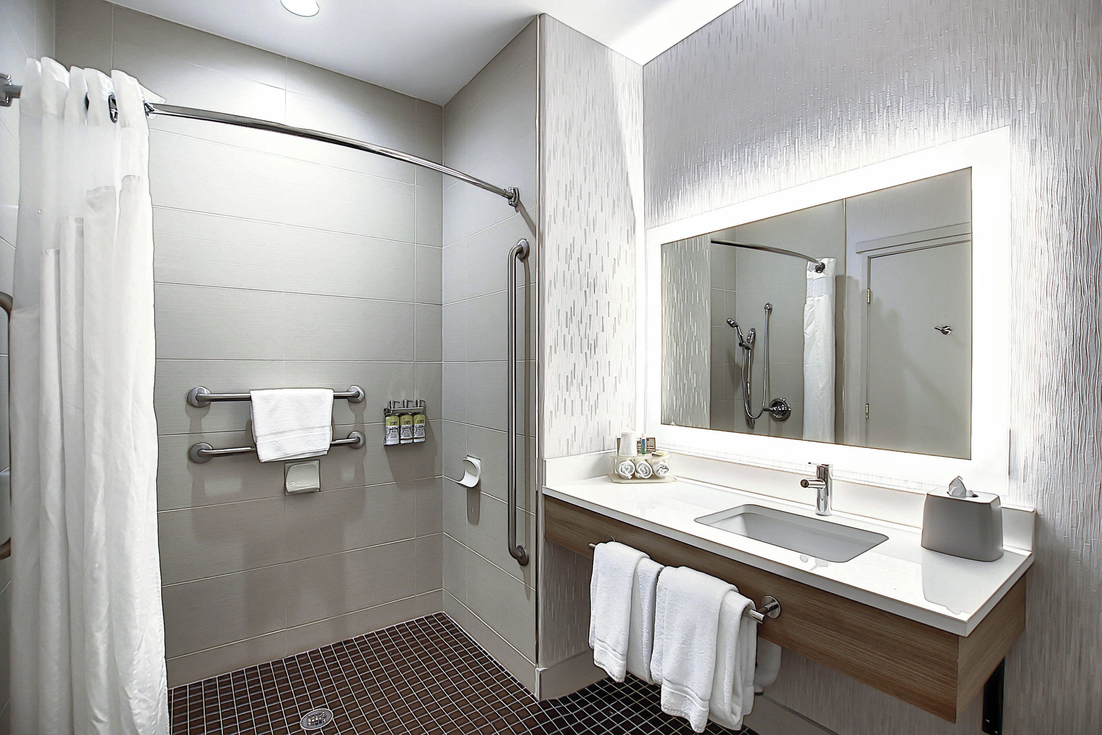 Un baño moderno con ducha, lavamanos, espejo y toallero.
