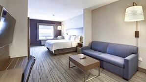 A hotel room with a bed, a sofa, a TV, a lamp, and a window. - Holiday Inn Express Airport-Calgary by IHG (Calgary)