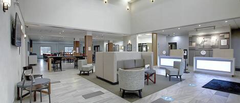 A spacious lobby with a reception desk, seating area, and a dining section.