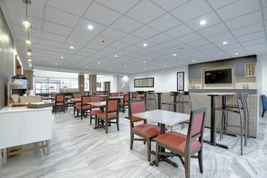 A restaurant with multiple tables and booths, a tiled floor, and a flat-screen TV mounted on the wall. - Holiday Inn Express Airport-Calgary by IHG (Calgary)