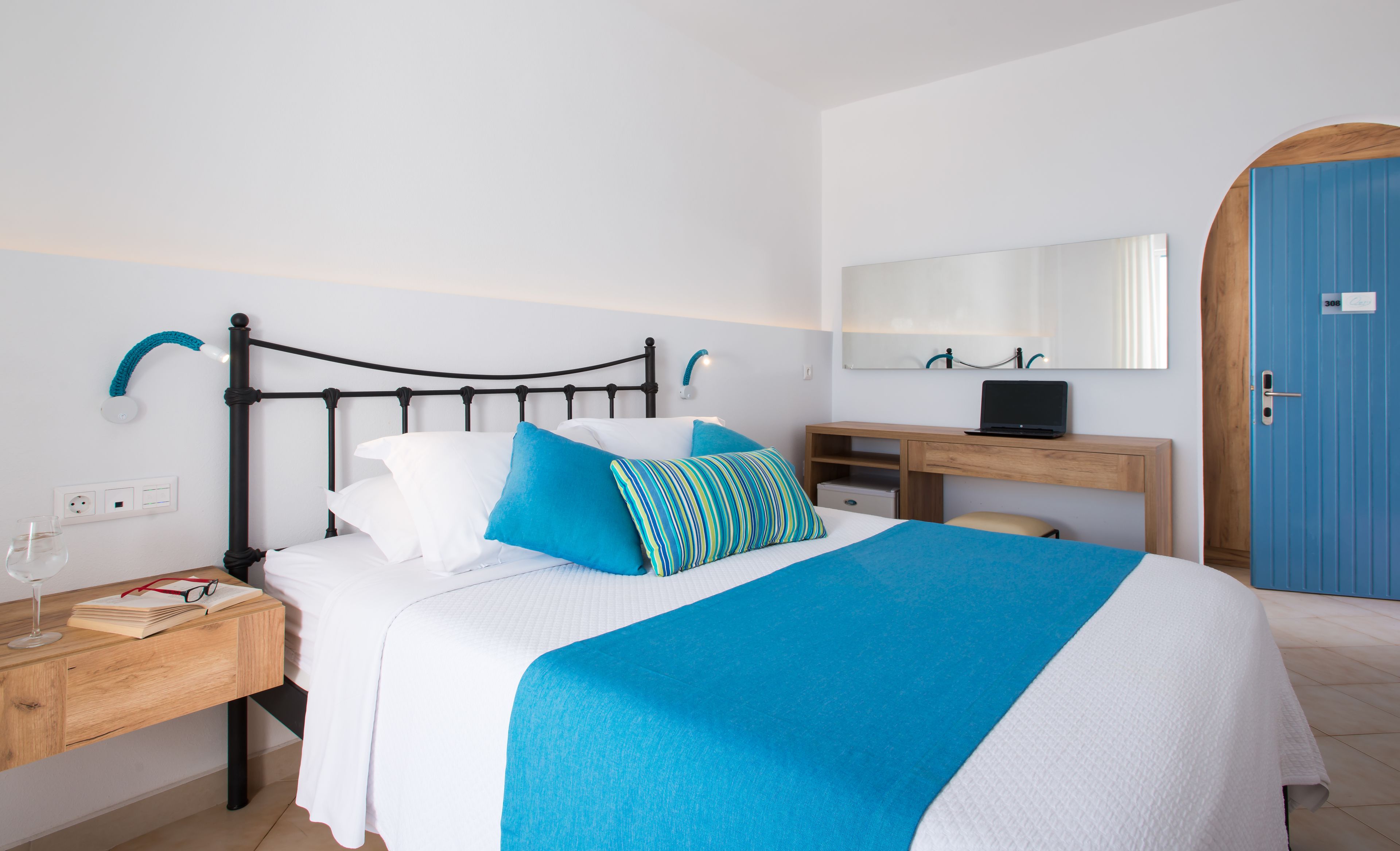 A neatly arranged bedroom with a bed, bedside table, and a desk with a laptop.