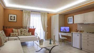 Un salon confortable avec un canapé, une table à manger, un téléviseur et un coin cuisine équipé de placards et d’un réfrigérateur.