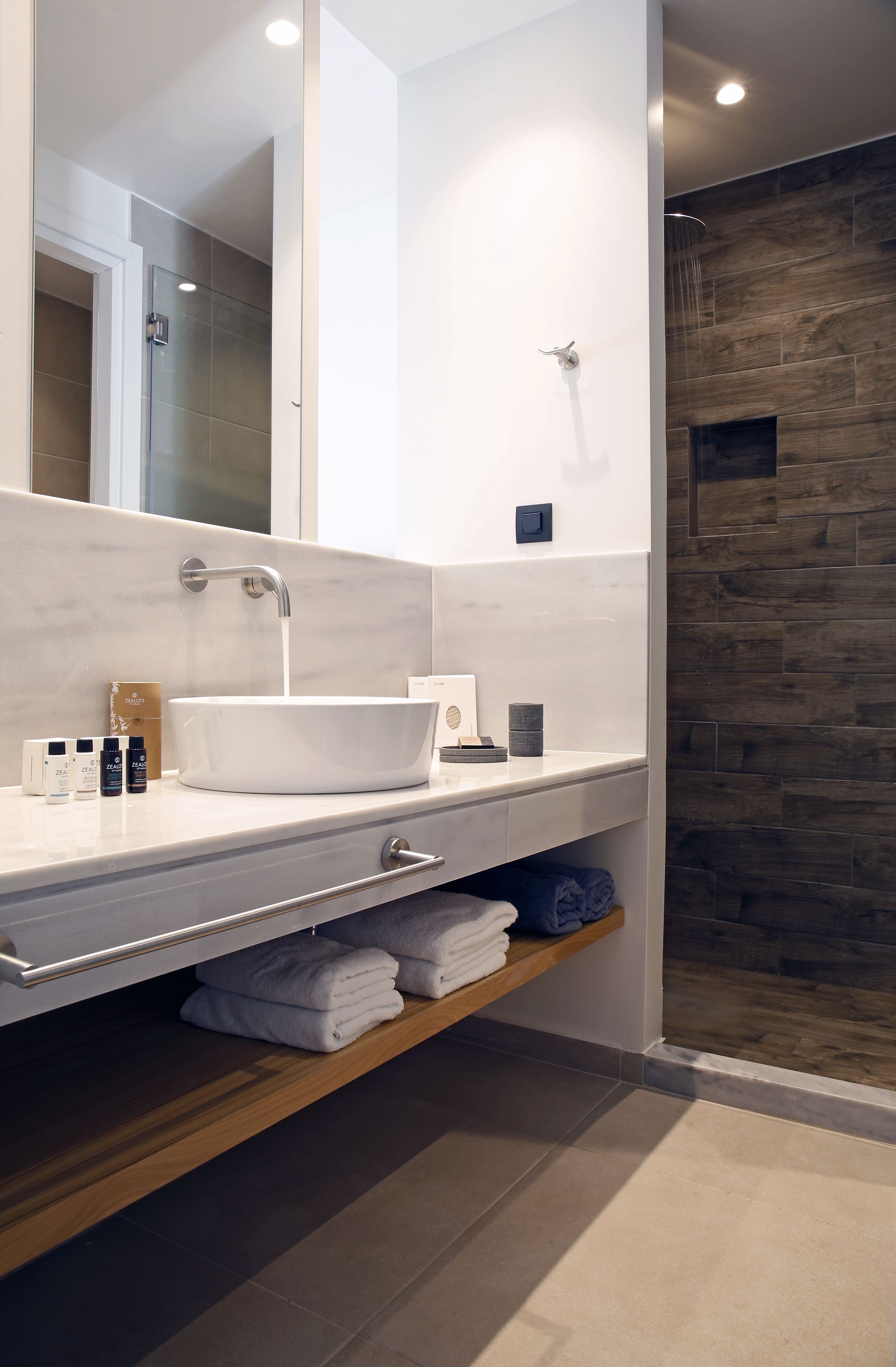 A modern bathroom with a white sink, a large mirror, and a shower area.