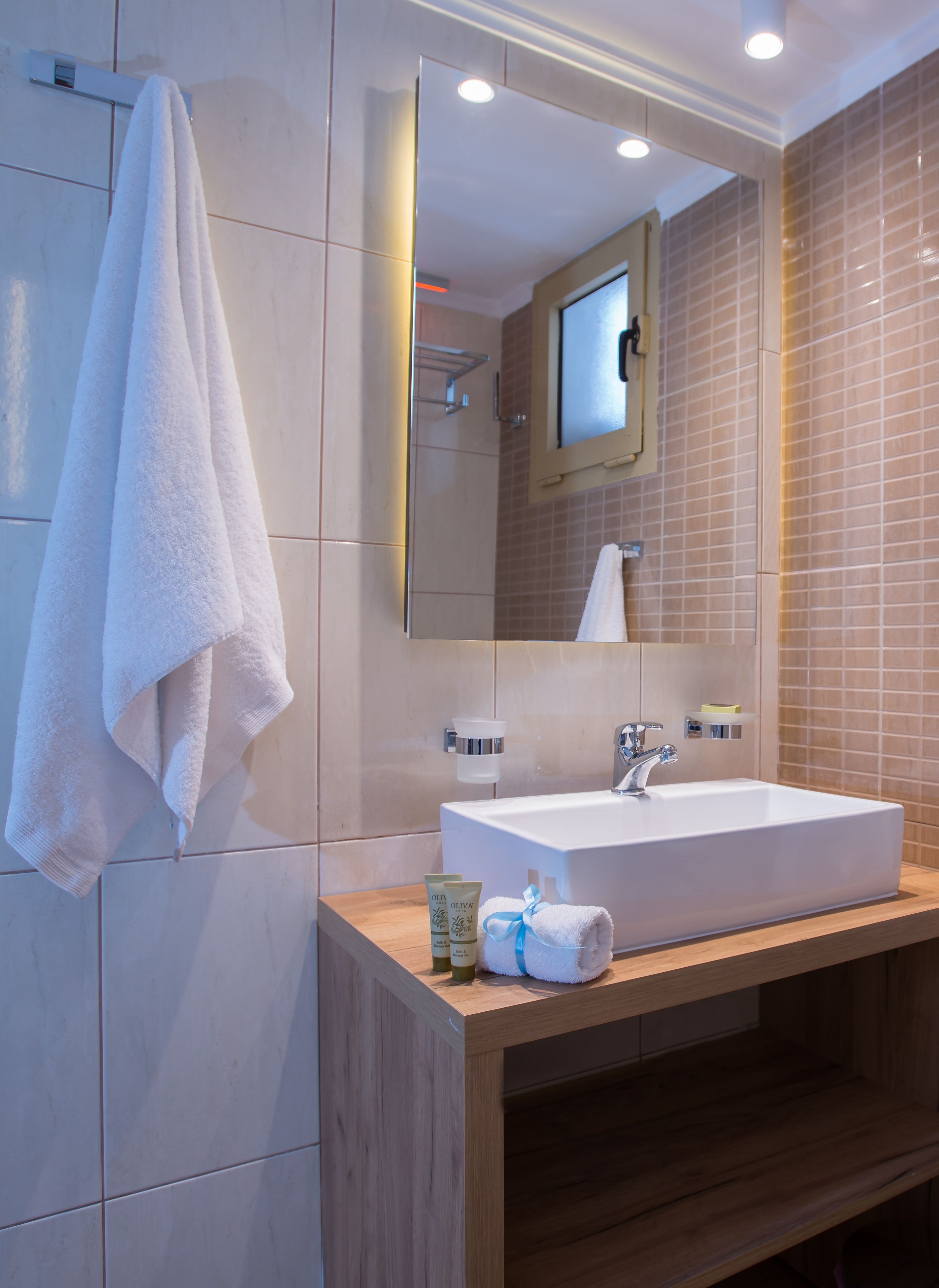 Un baño moderno con un espejo grande, lavamanos blanco y tocador de madera.
