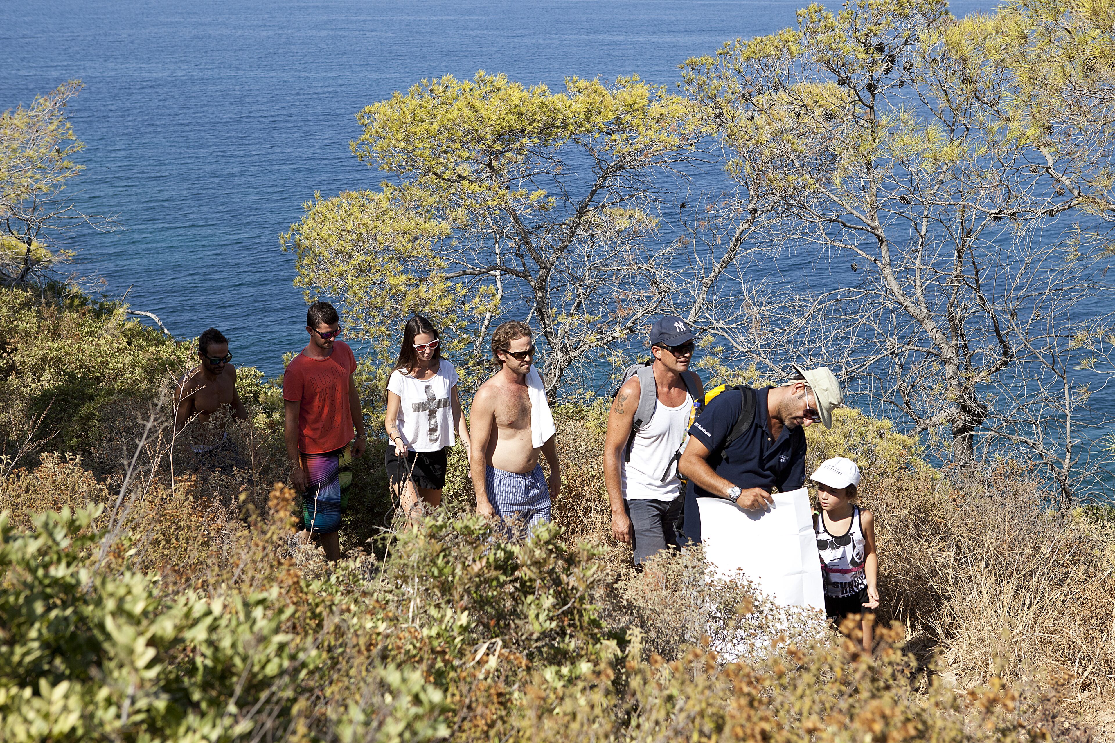 A group of people standing on a grassy hillside with a view of the sea.