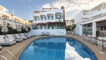 A swimming pool with lounge chairs and umbrellas, a building labeled "Oasis," and a clear sky.