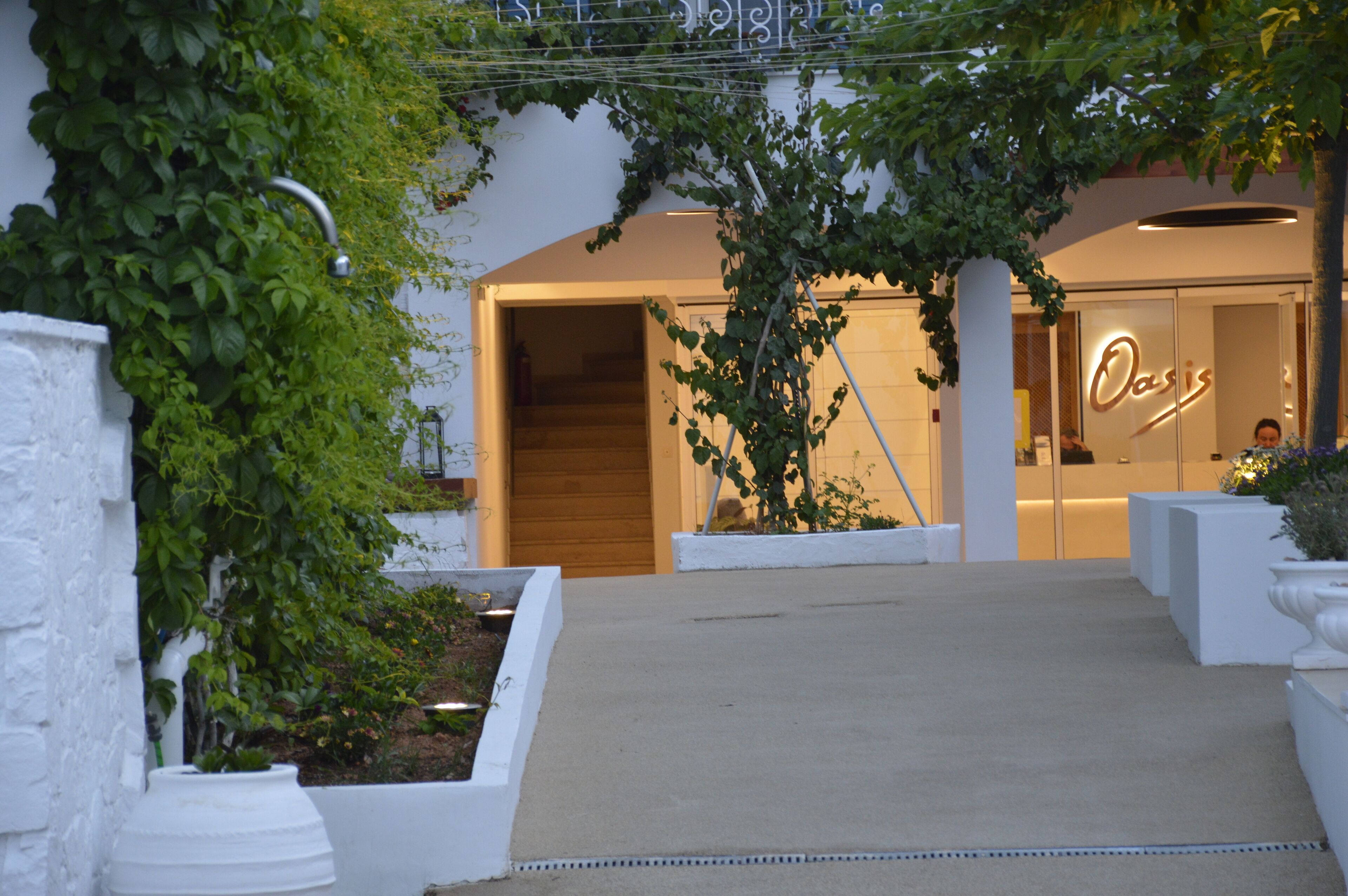 A hotel entrance with a modern design, a visible staircase, and a sign that reads "Oasis".