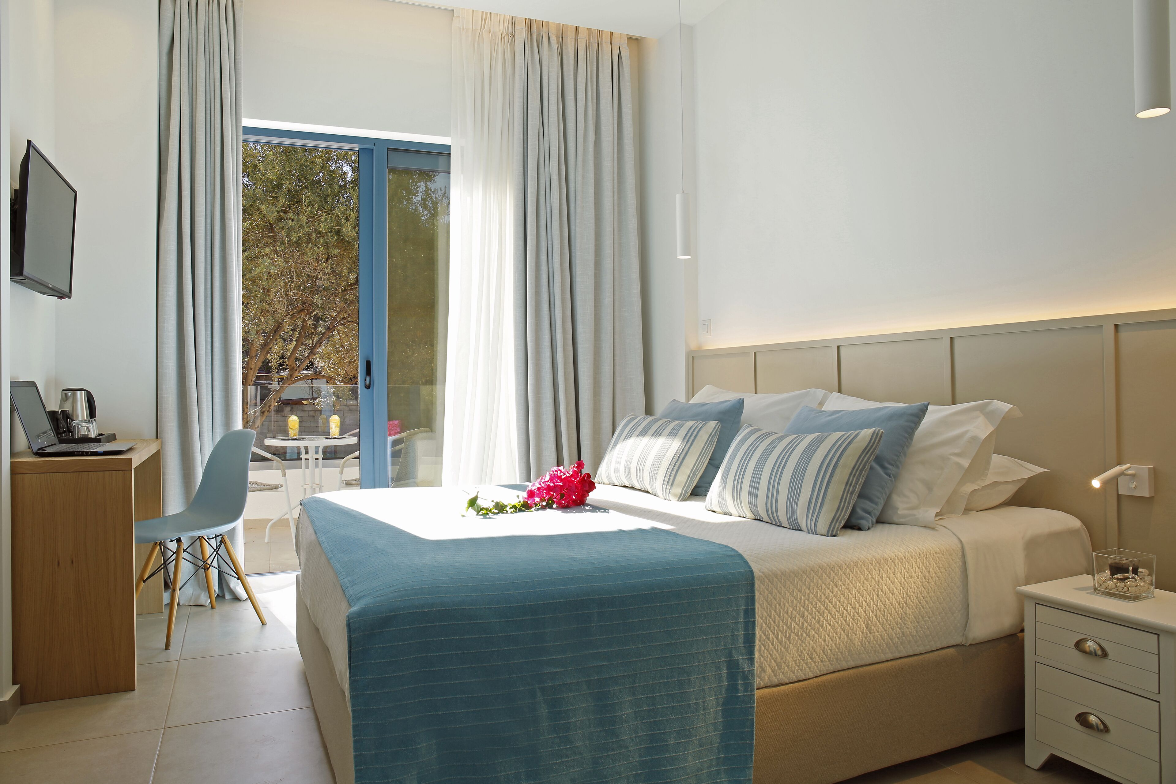 Une chambre d’hôtel comprenant un lit, une table de chevet, un bureau avec un ordinateur portable et une chaise.