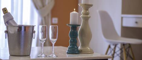 A table with a champagne bottle, two glasses, and two candles.