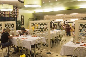Un restaurant avec des nappes blanches, des chaises blanches et un mur vert.
