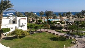 Een resort met een zwembad, palmbomen en uitzicht op zee.