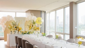 Un salón de conferencias con una larga mesa dispuesta para una reunión, ventanas amplias y vistas a la ciudad.
