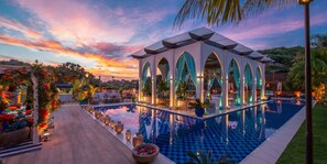 Ein Poolbereich mit Pavillon, Sitzgelegenheiten und Blick auf den Sonnenuntergang.