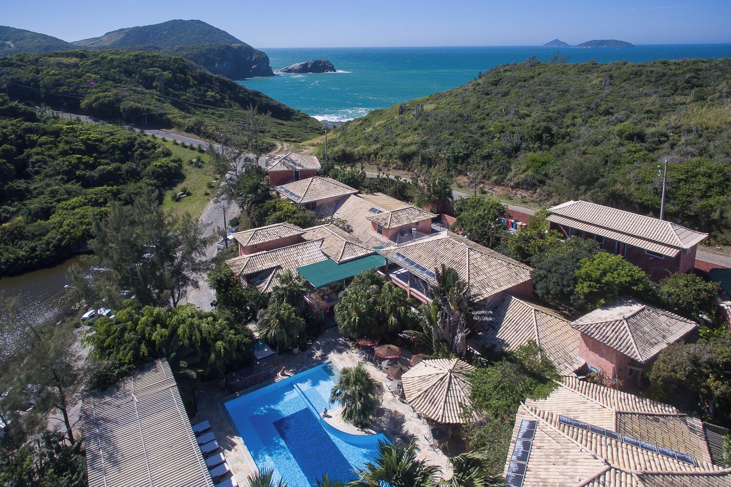Un resort con diversi edifici, una piscina e vista sull'oceano.