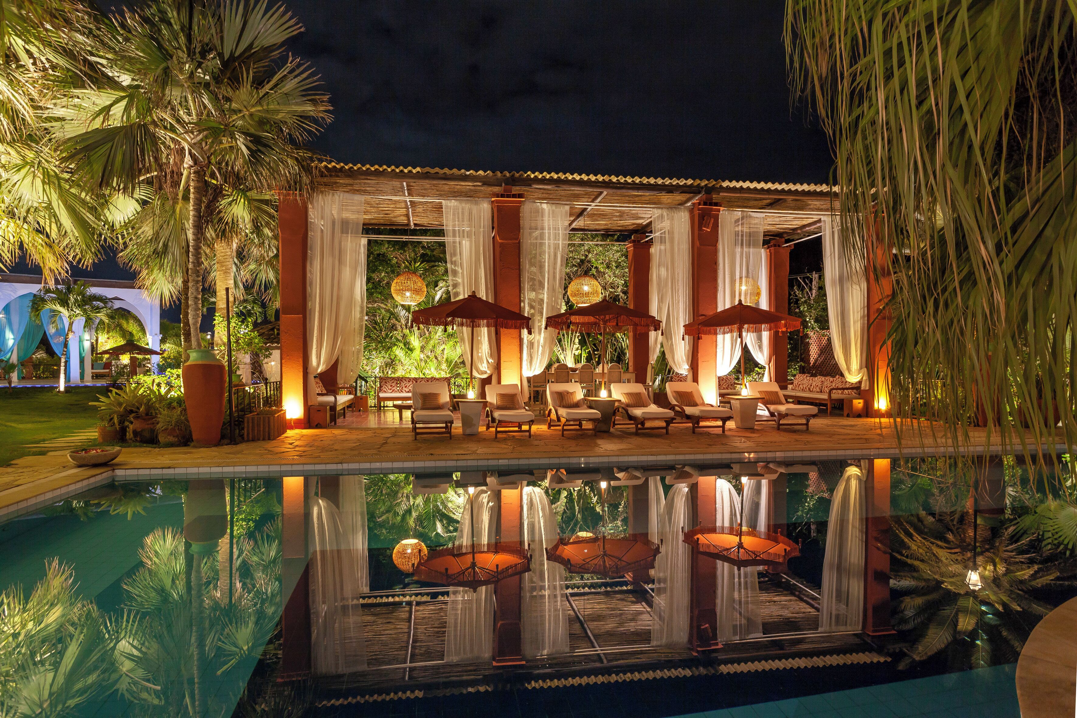 A poolside area with lounge chairs, umbrellas, and a water feature.