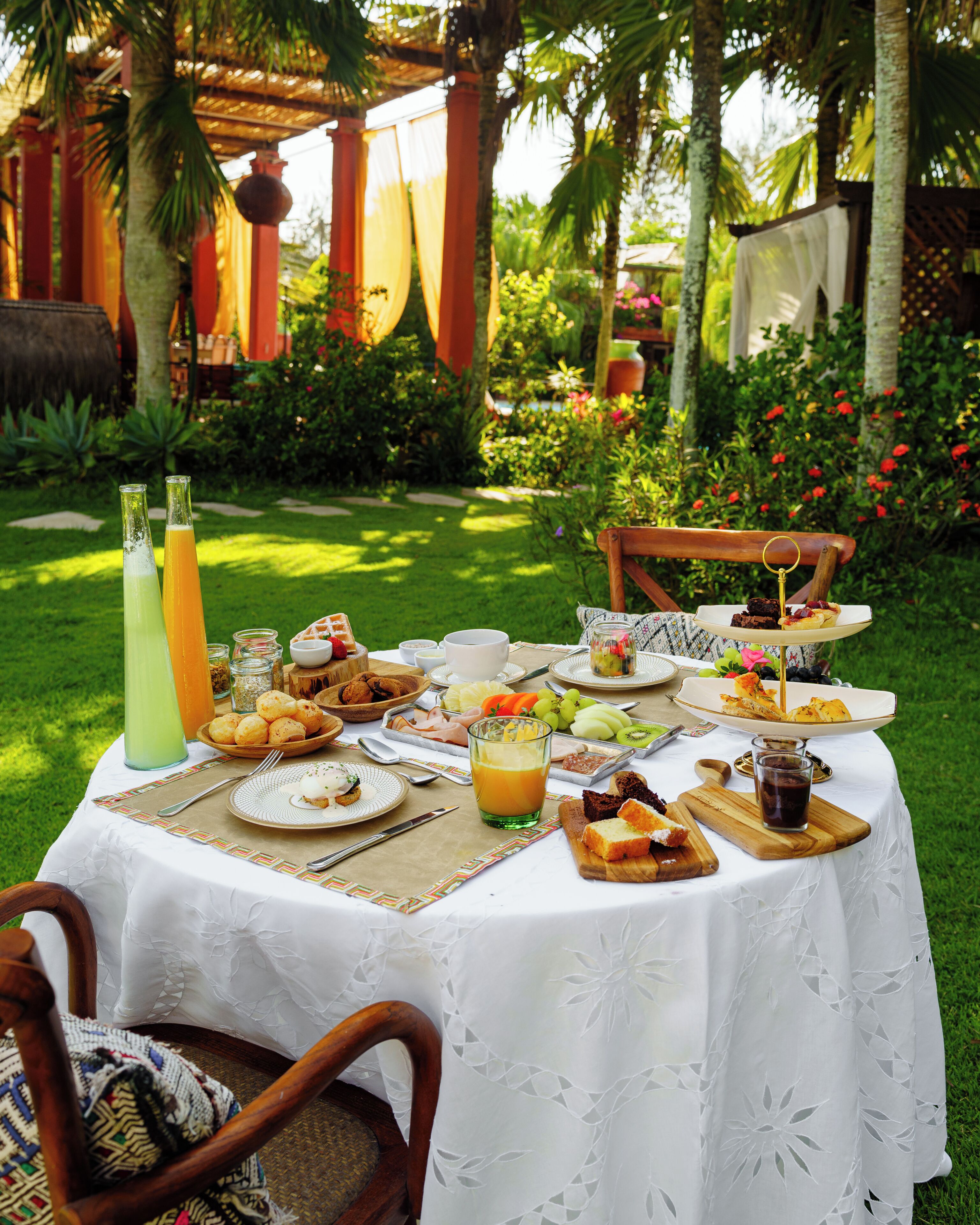 An outdoor dining setup with a table set for breakfast, including various foods and drinks.