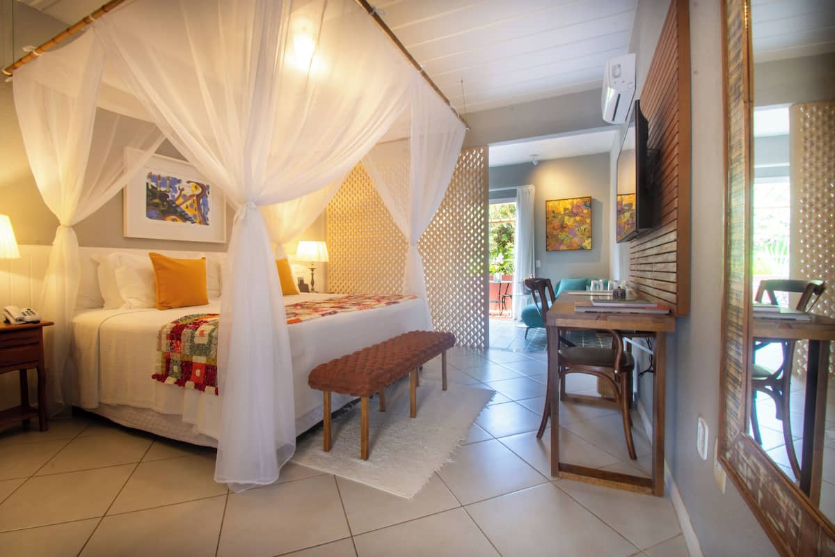Une chambre à coucher avec un lit à baldaquin, une table de chevet, un banc et un bureau avec une chaise.