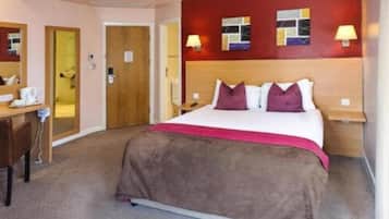 Een hotelkamer met een bed, een bureau, een stoel, een spiegel en een deur.