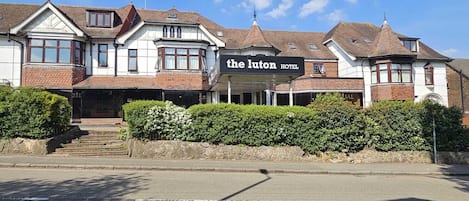 A two-story building with a sign for "The Luton Hotel" on the ground floor.