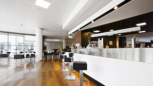 Un espace bar moderne doté d’un long comptoir, de nombreux tabourets et d’un plancher en bois poli.