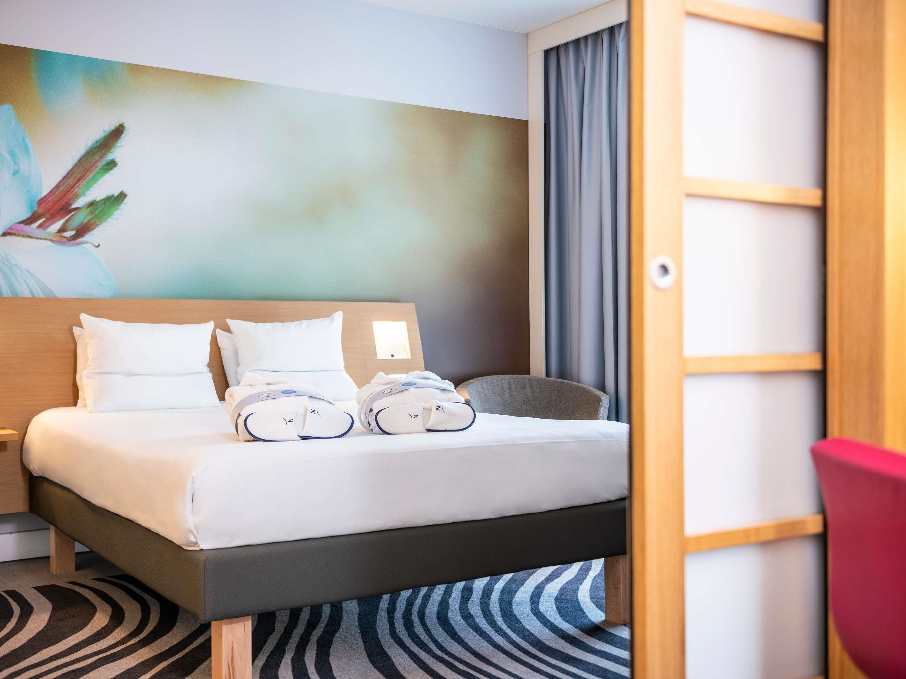 Une chambre d’hôtel avec un lit, des oreillers, une table de chevet, une chaise et un tableau au mur.