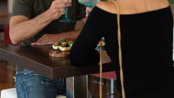 Un homme et une femme sont assis à une table, devant des boissons et des amuse-gueules.