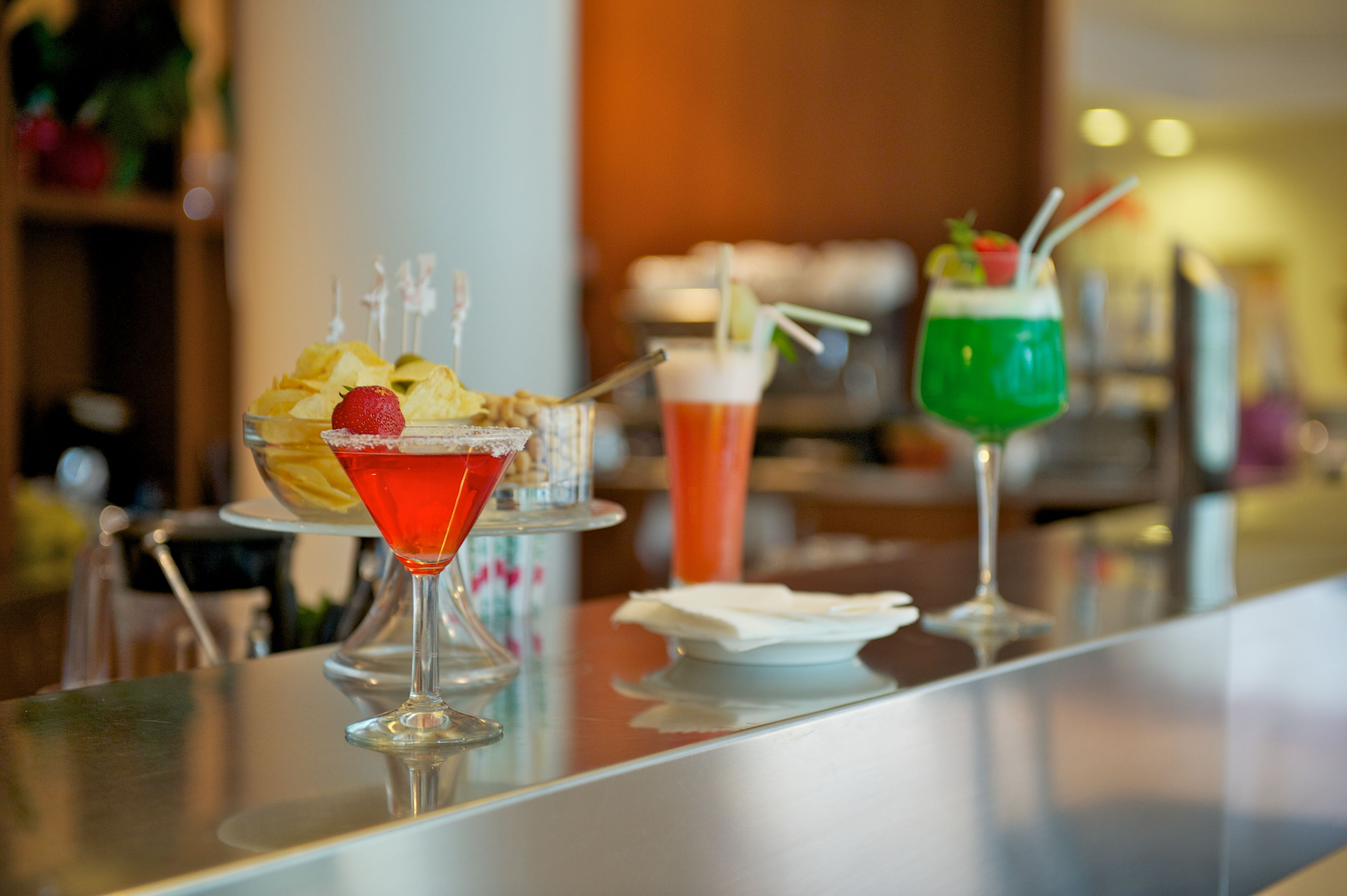 Una zona de bar con tres cócteles, cada uno decorado con frutas y pajitas.